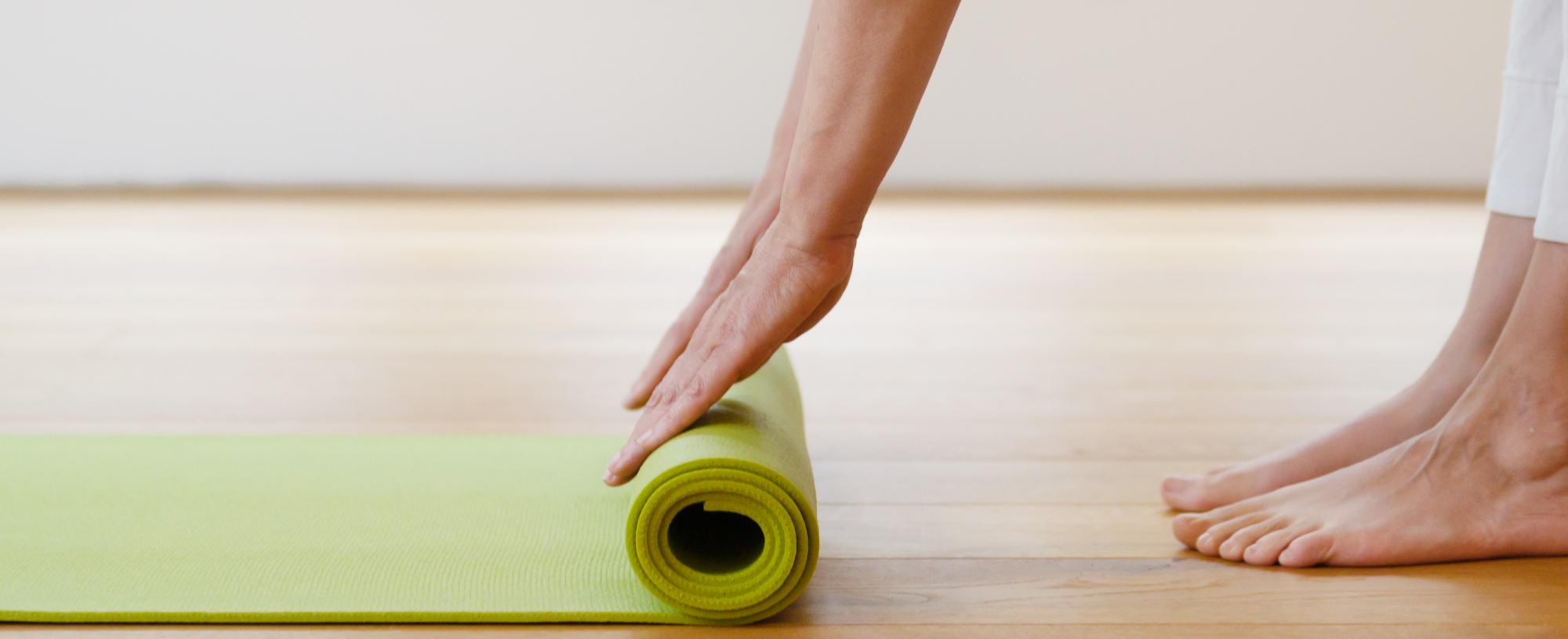 Raum für Yoga Iserbrook, Yogaraum Detail, grüne Yogamatte Raum für Yoga Iserbrook, Yogaraum Detail, Hände rollen eine grüne Yogamatte auf